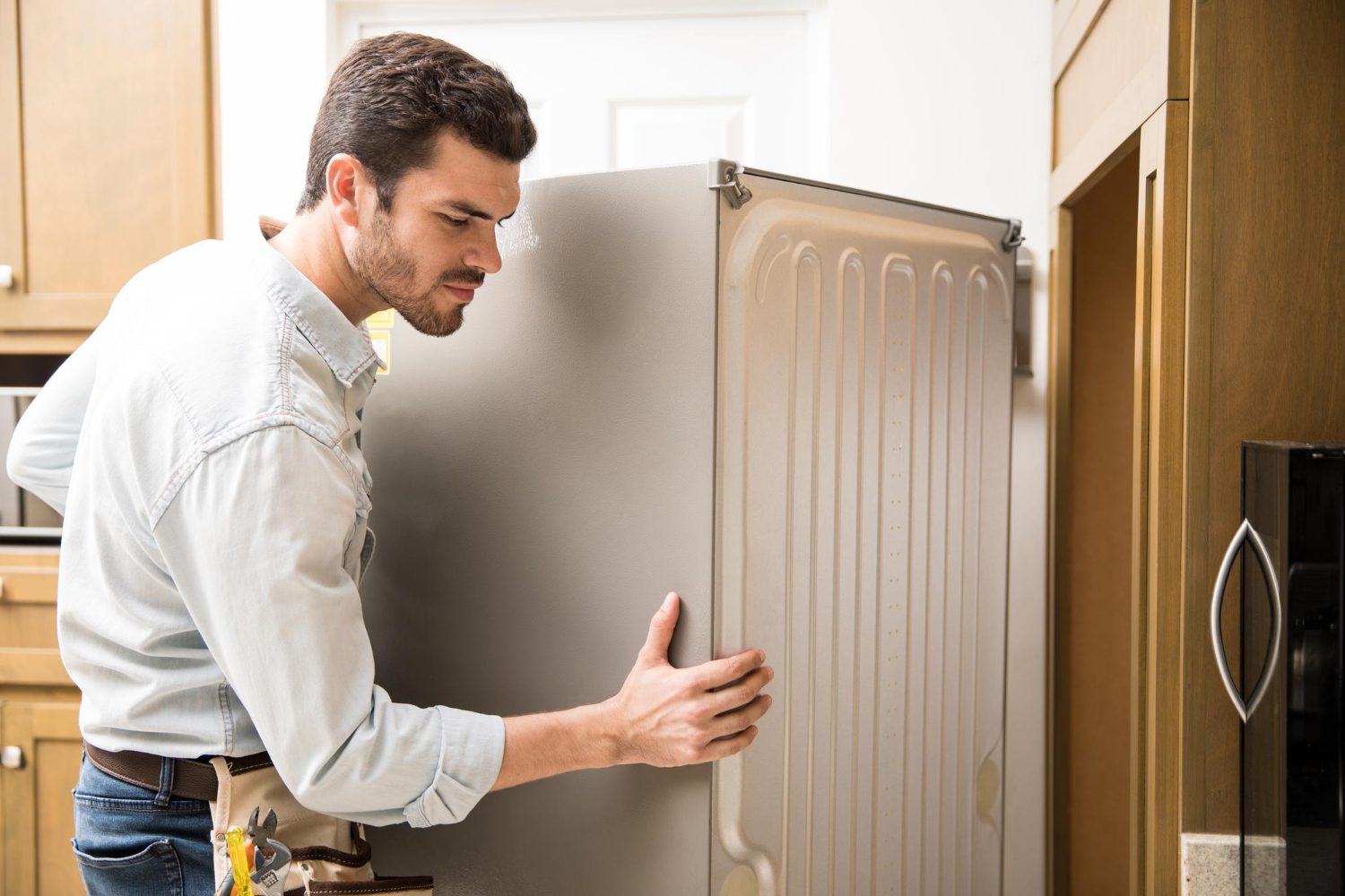 young-man-working-as-electrician-exposing-back-fridge-check-repair-it young man working as an electrician exposing the back of a fridge to check and repair it